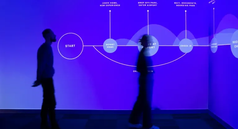 Two people standing in silhouette in front of a glowing blue wall with a data-visualization timeline across it