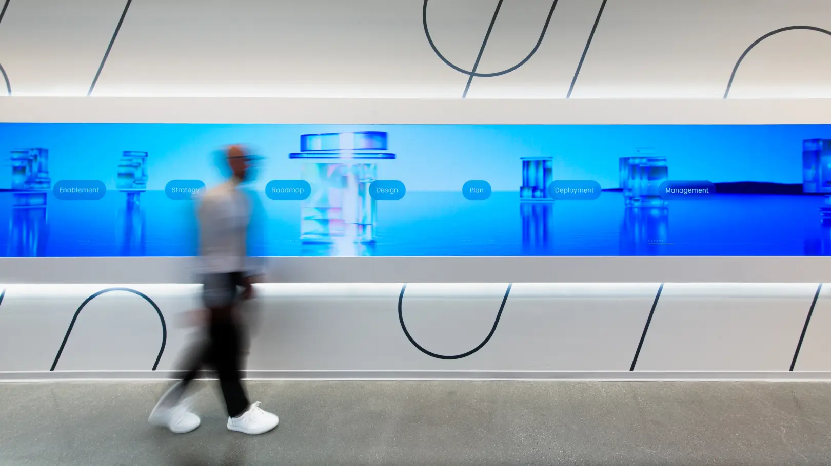 Long exposure shot of person walking left to right across a very wide screen showing blue graphics