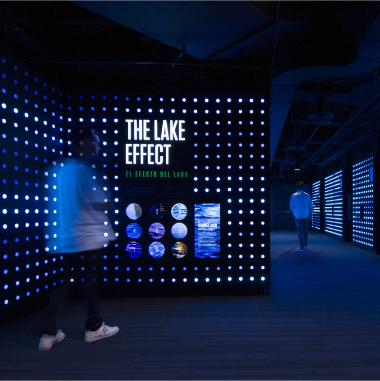 A person looking at The Lake Effect light wall, glowing blue and white