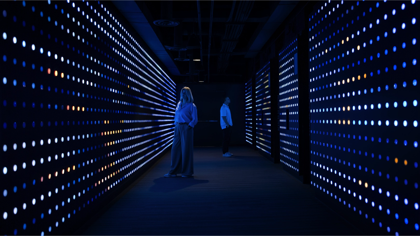 Two people looking at the Lake Effect light walls, glowing blue and orange