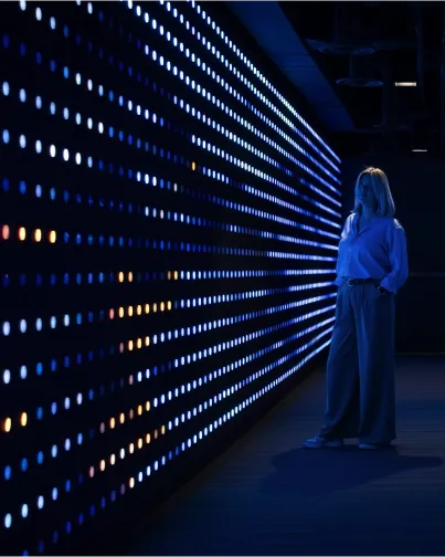 A person looking at the Lake Effect light wall, glowing blue and orange