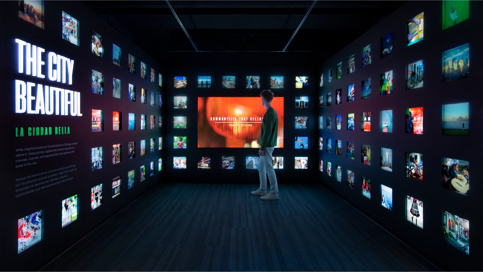 A person looking at The City Beautiful installation, with images in the space surrounding a large screen