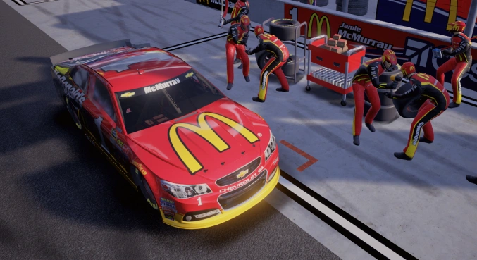 McDonalds NASCAR car sits in the raceway pit as five members of the pit crew approach with new tires and gas